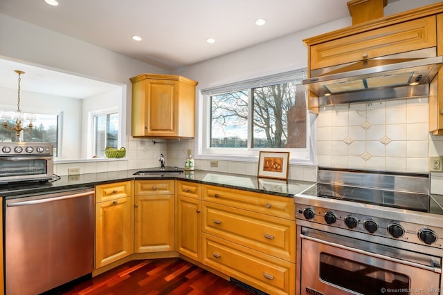 kitchen featuring ventilation hood, dark stone counters, a toaster, a sink, and appliances with stainless steel finishes