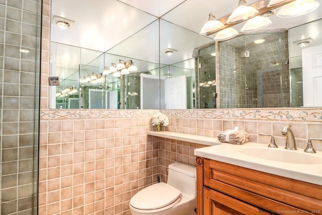 bathroom with vanity, tile walls, toilet, and a stall shower