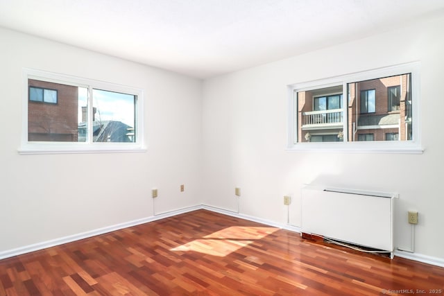 empty room featuring baseboards, radiator, and wood finished floors