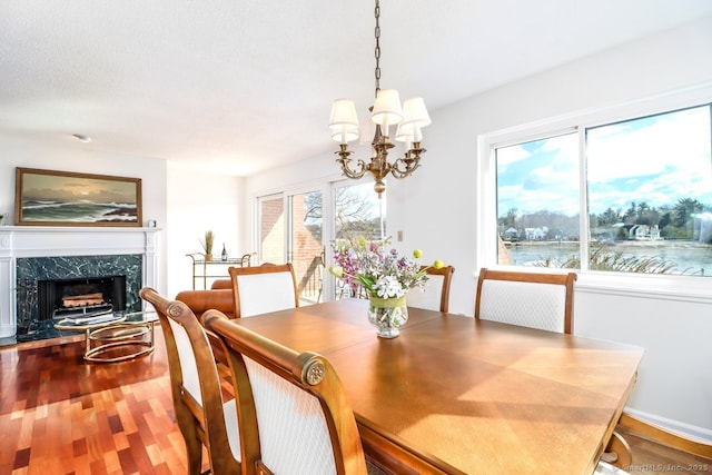 dining room featuring wood finished floors, a high end fireplace, and a chandelier