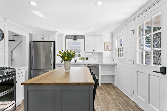 kitchen with a healthy amount of sunlight, appliances with stainless steel finishes, wood counters, and wood finish floors