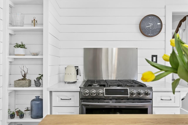 kitchen featuring gas stove, open shelves, white cabinets, and light countertops