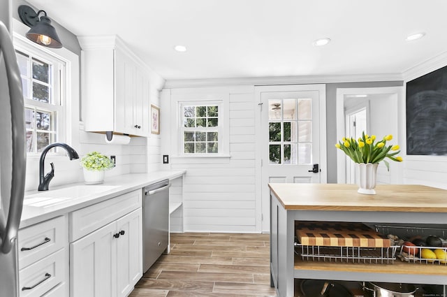 kitchen with a sink, white cabinetry, stainless steel appliances, light countertops, and wood tiled floor
