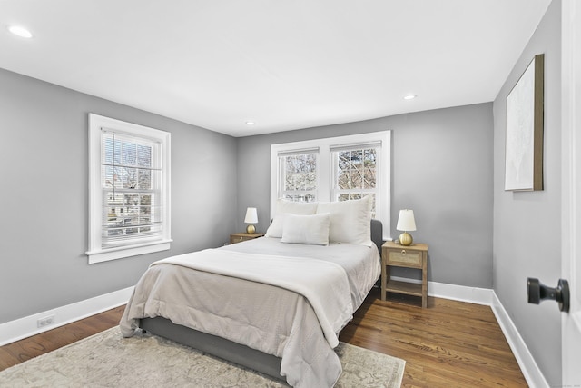 bedroom with baseboards, multiple windows, and wood finished floors