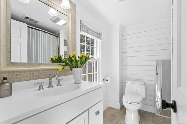 bathroom featuring visible vents, toilet, wooden walls, crown molding, and vanity