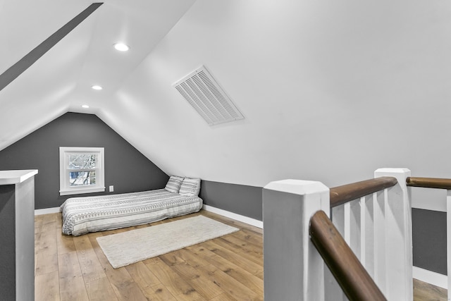 bedroom with visible vents, lofted ceiling, baseboards, and hardwood / wood-style flooring