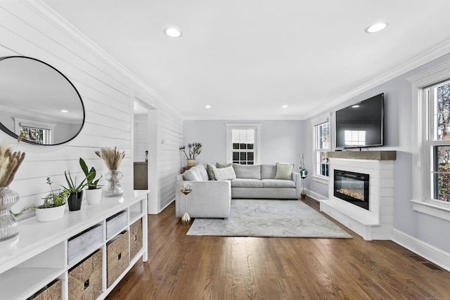living room with dark wood finished floors, crown molding, visible vents, and a glass covered fireplace