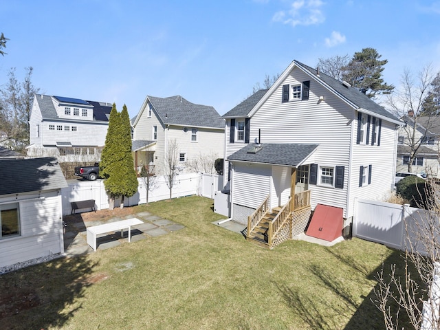 back of property with a yard, a residential view, a shingled roof, and a fenced backyard