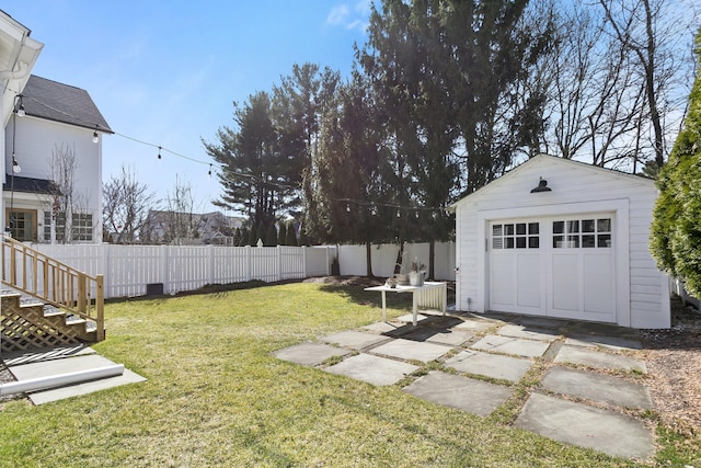 view of yard with a garage, an outbuilding, concrete driveway, and fence