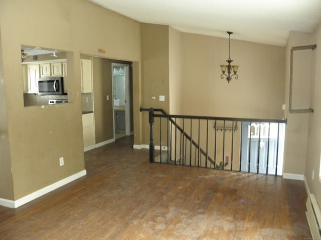 empty room featuring an inviting chandelier, baseboards, lofted ceiling, and wood finished floors