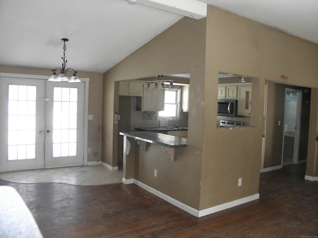 kitchen with wood finished floors, lofted ceiling with beams, a sink, stainless steel microwave, and cream cabinets