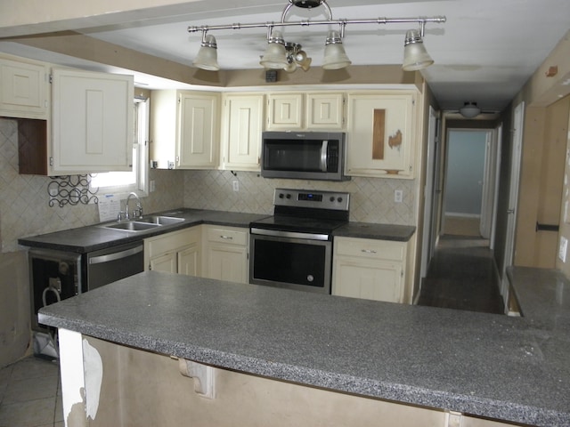 kitchen featuring tile patterned floors, a sink, dark countertops, backsplash, and stainless steel appliances