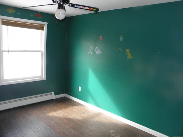 empty room featuring baseboard heating, ceiling fan, baseboards, and dark wood-style flooring