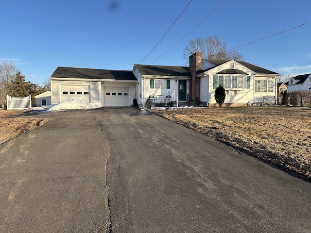 ranch-style house with a garage, driveway, a chimney, and fence