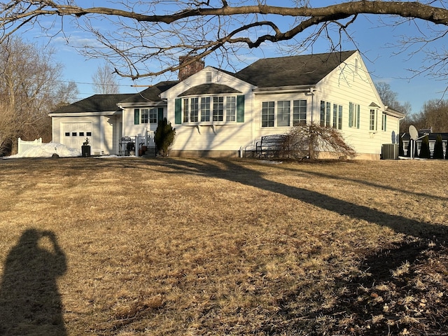 view of front of property with a garage, a chimney, and a front lawn