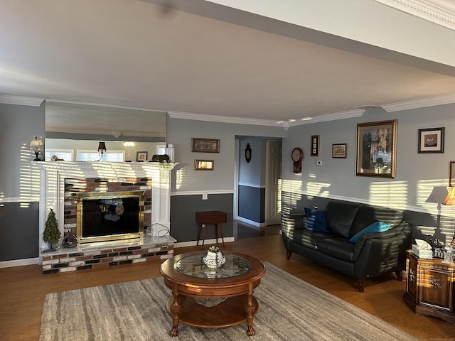 living area with ornamental molding, a fireplace, and wood finished floors