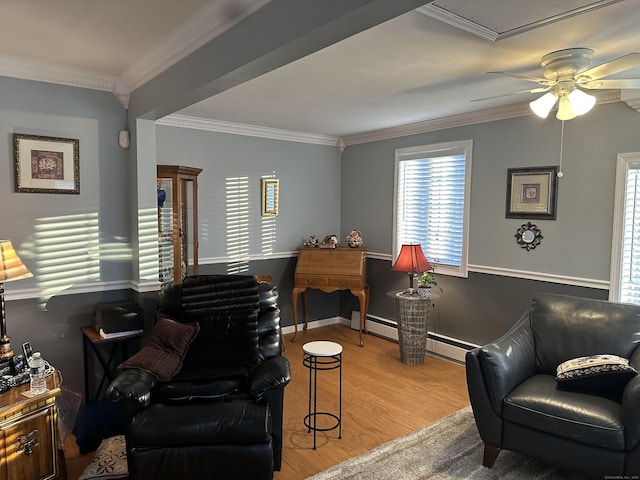 living area with ceiling fan, a baseboard heating unit, baseboards, ornamental molding, and light wood finished floors