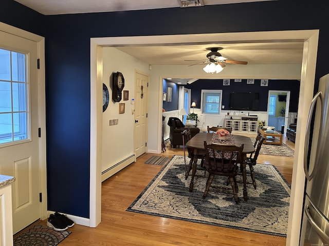 dining room with light wood-style floors, baseboards, baseboard heating, and a ceiling fan