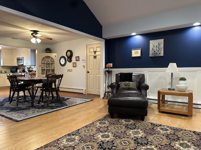 living room featuring a baseboard heating unit, baseboard heating, wood finished floors, and a wainscoted wall