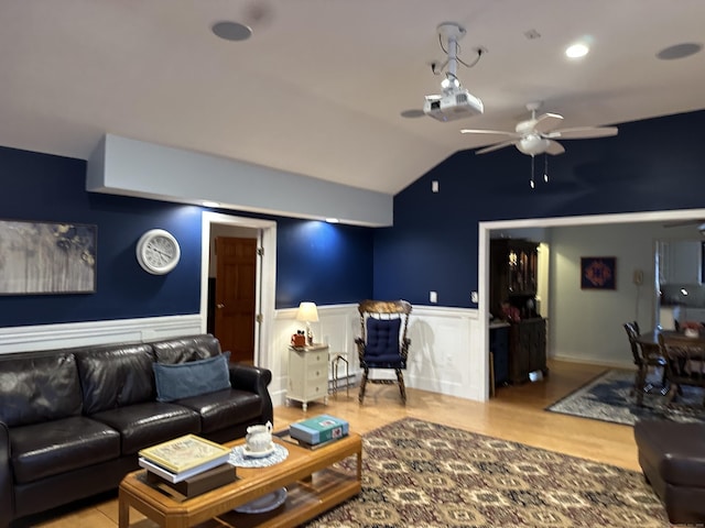 living area featuring vaulted ceiling, ceiling fan, wainscoting, and wood finished floors