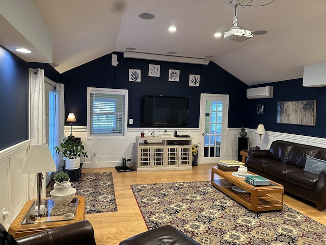 living area featuring lofted ceiling, a wainscoted wall, and a wall unit AC