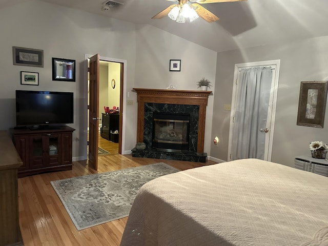 bedroom with a fireplace, lofted ceiling, visible vents, wood finished floors, and baseboards