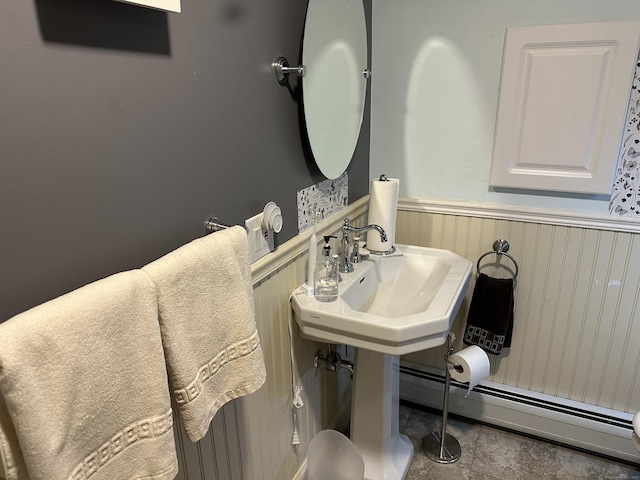 bathroom featuring baseboard heating, wainscoting, and a sink