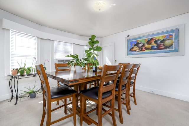 dining space with baseboards and light colored carpet