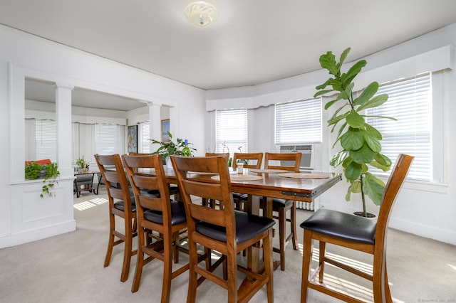 dining room featuring baseboards, cooling unit, decorative columns, and light colored carpet