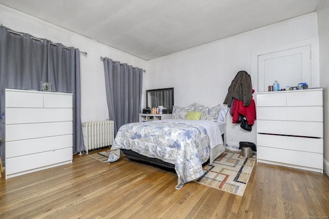 bedroom with radiator heating unit and wood finished floors