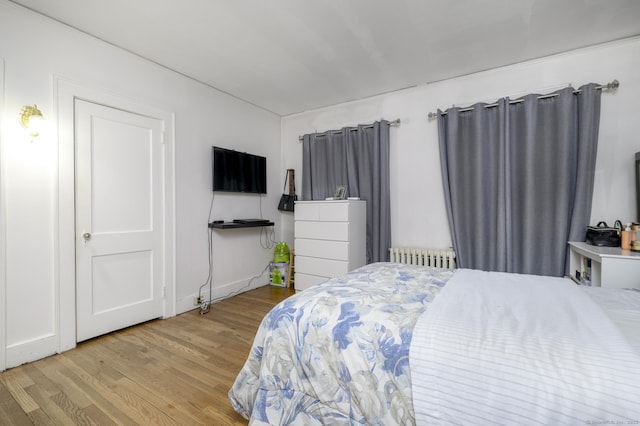 bedroom with radiator heating unit and wood finished floors