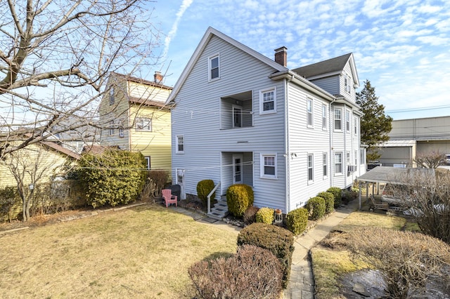 back of property featuring a chimney and a lawn