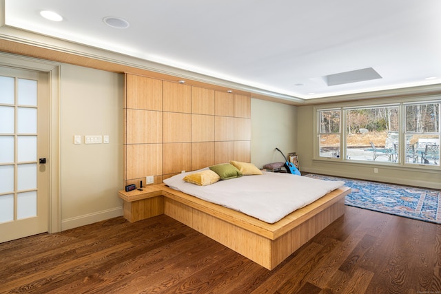 bedroom with dark wood-type flooring, a raised ceiling, and baseboards