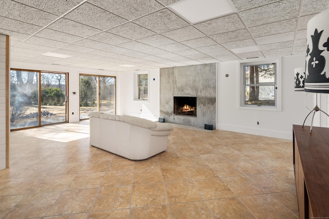 unfurnished living room with a drop ceiling, a high end fireplace, and baseboards