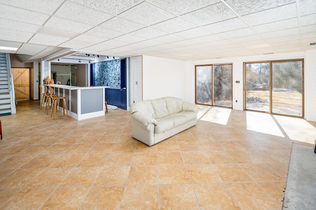 unfurnished living room featuring a drop ceiling and stairway