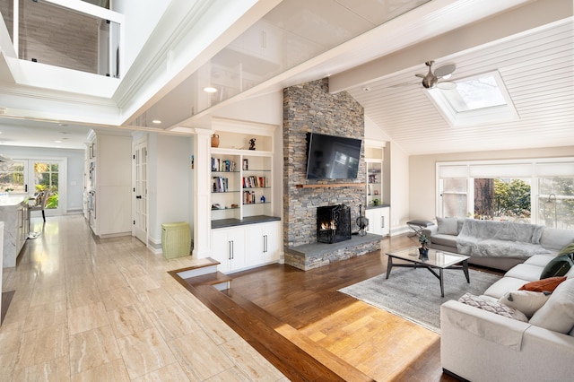 living room featuring light wood finished floors, ceiling fan, a stone fireplace, high vaulted ceiling, and beam ceiling