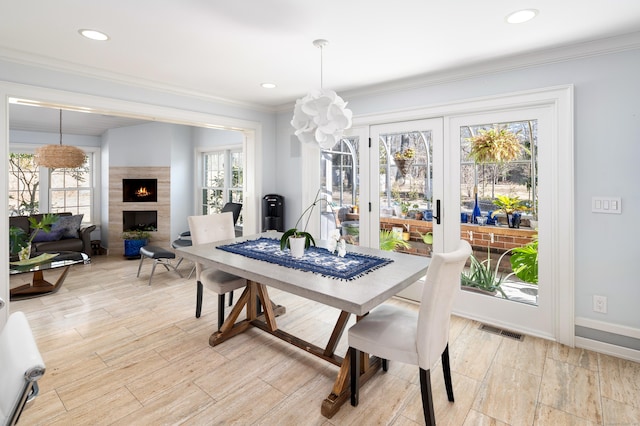 dining room featuring ornamental molding, a tile fireplace, visible vents, and baseboards