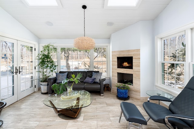 sunroom / solarium featuring wood ceiling, vaulted ceiling with skylight, a tile fireplace, and french doors