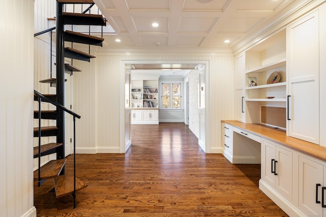 hallway featuring built in shelves, dark wood-style flooring, coffered ceiling, and crown molding