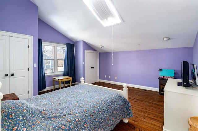 bedroom featuring lofted ceiling, attic access, baseboards, and wood finished floors