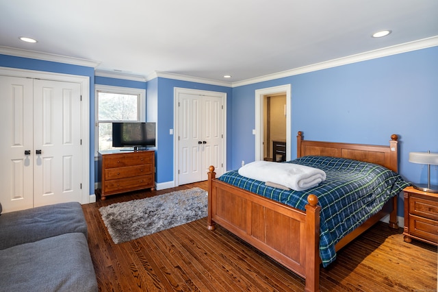 bedroom featuring recessed lighting, wood finished floors, baseboards, ornamental molding, and two closets