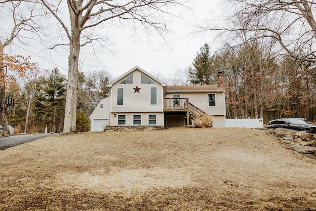 exterior space with a chimney, stairway, fence, a deck, and a garage