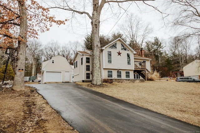 view of front of property featuring an outbuilding, stairway, a chimney, and a detached garage