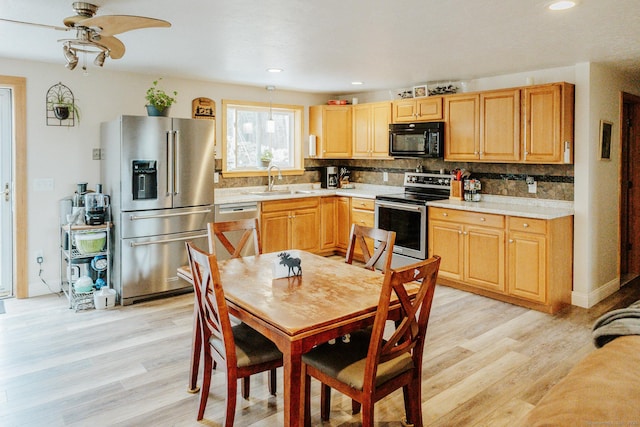 kitchen featuring stainless steel appliances, light wood finished floors, backsplash, and a sink