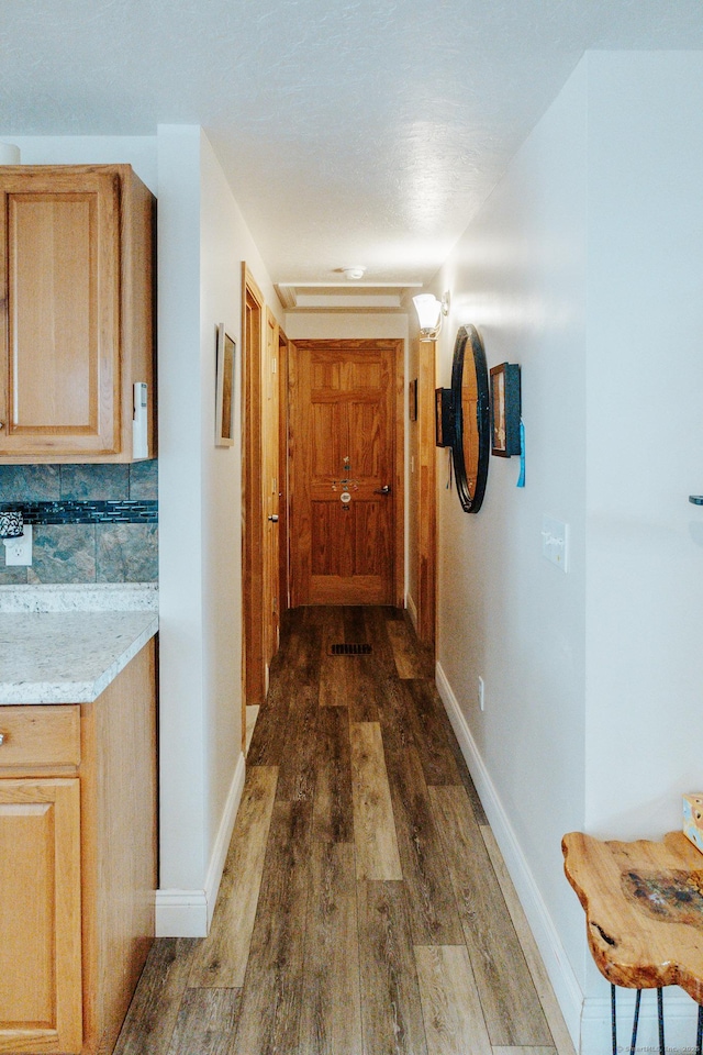 corridor featuring baseboards and dark wood finished floors