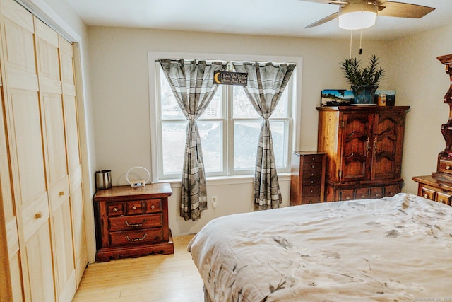 bedroom featuring light wood-type flooring, a ceiling fan, and a closet