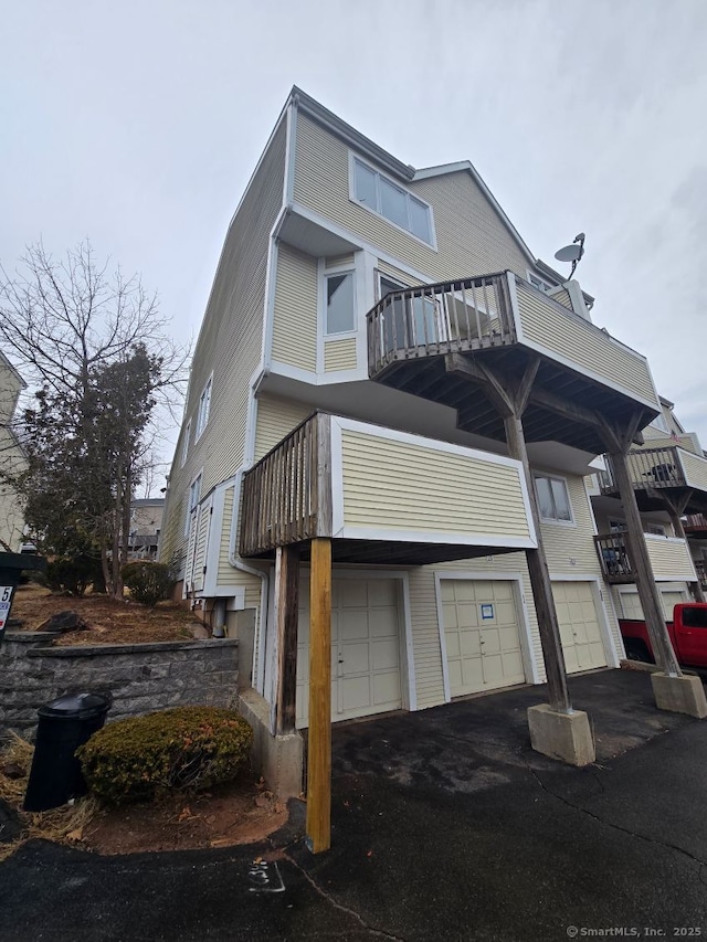 townhome / multi-family property featuring a garage, a balcony, and aphalt driveway