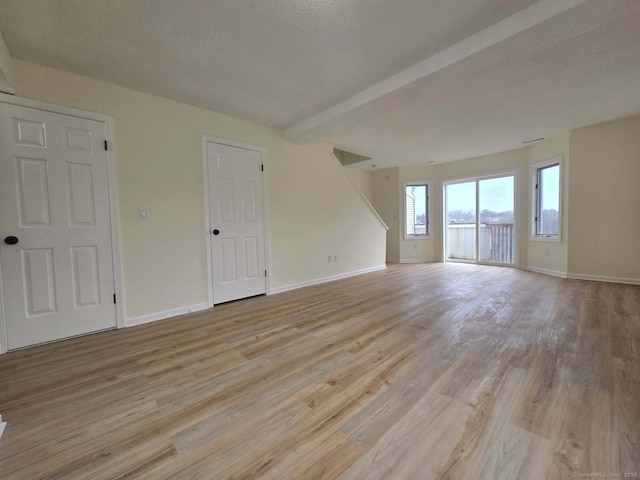 interior space with beamed ceiling, light wood-type flooring, and baseboards