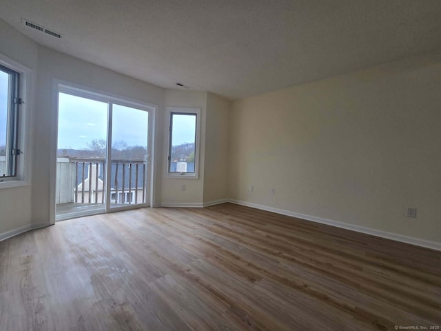 empty room with baseboards, visible vents, and wood finished floors