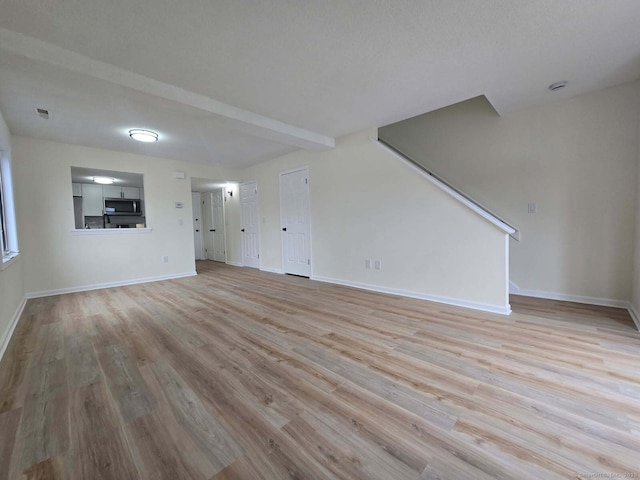 unfurnished living room featuring visible vents, stairway, baseboards, and wood finished floors